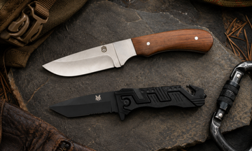 Compact full tang hunting knife with wood handle and black sheath displayed on a log at camp