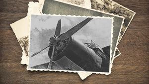 Vintage black-and-white photo of a radial-engine propeller aircraft on a wooden surface.